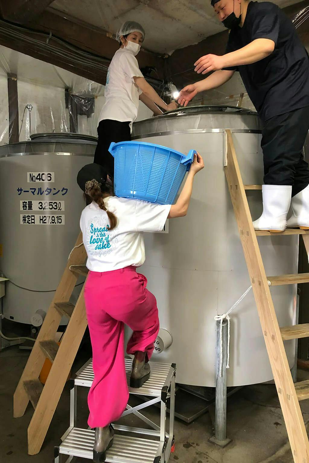 Rina and Azusa work with the Mitsutake brewing staff to add rice to the fermentation tank.