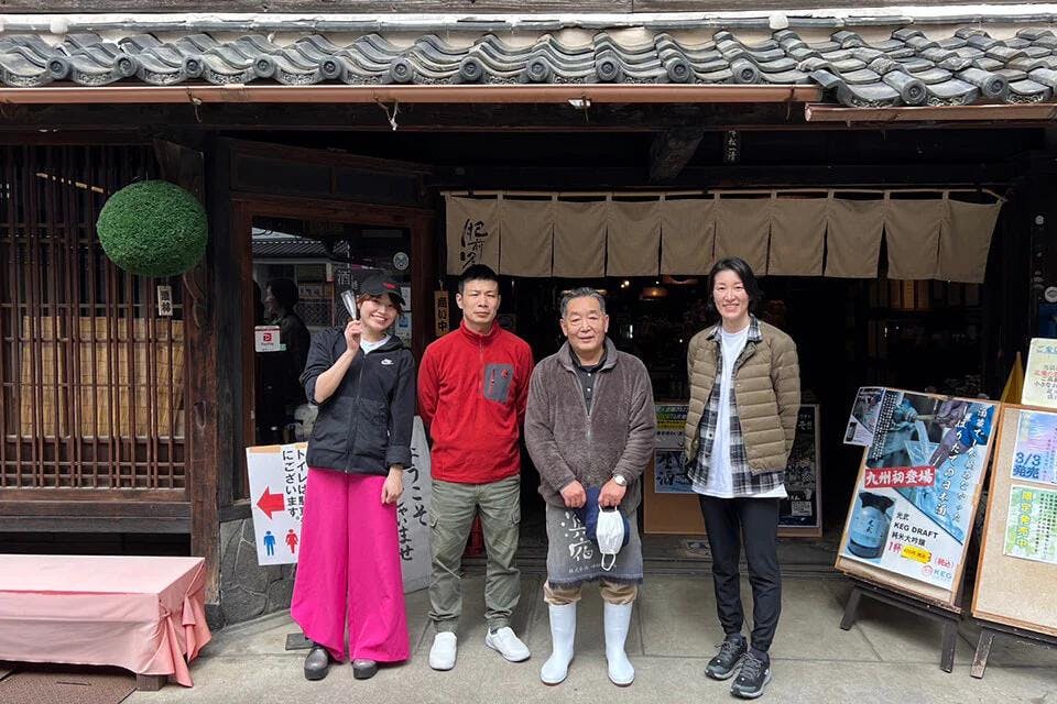 Rina, toji Ryuichi Yoshida, brewery staff member Kazukiyo Minematsu, and Azusa stand outside of the brewery shop. | Photo by Azusa K.