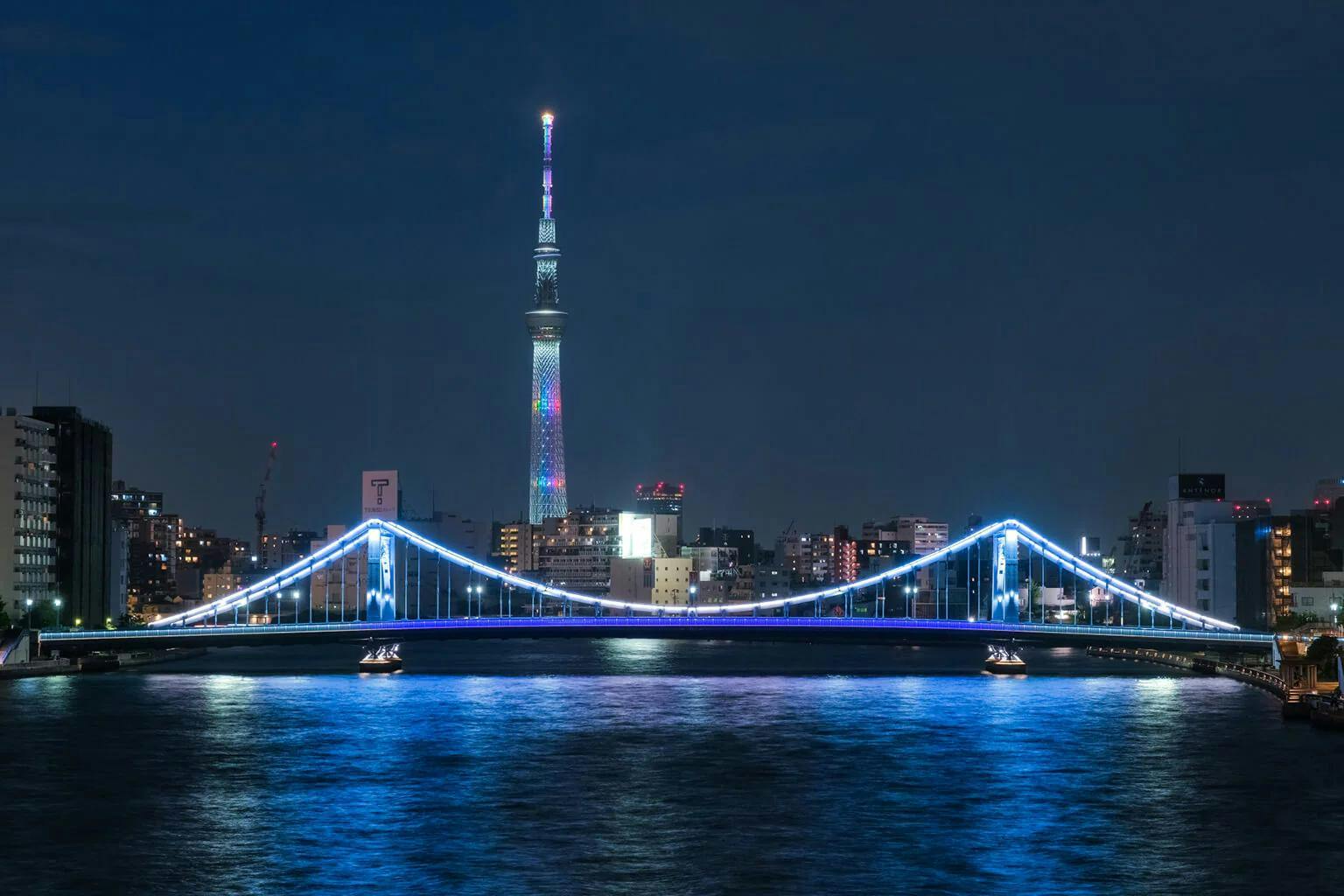 The Sumida River reflects the glow of the Tokyo Skytree and the Kiyosubashi Bridge at night