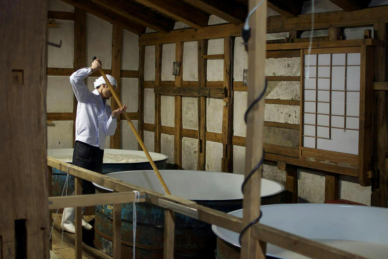 A “kurabito” (brewery worker) mixes the sake mash with a long pole called a “kaibo.”
