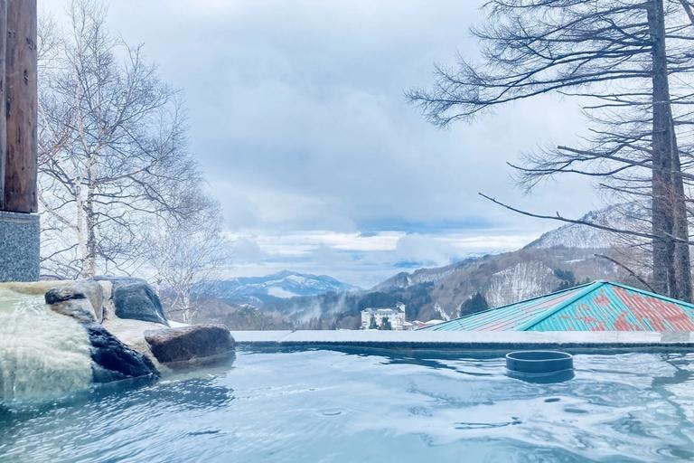 View of snow-covered mountains from an outdoor onsen.