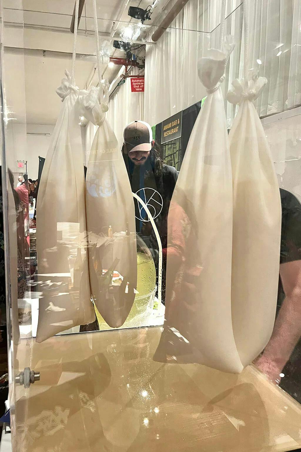Fresh sake drips freely from hanging bags of “moromi” (sake mash) to produce shizuku sake. Because this is a slow process, not enough sake is collected by the display to taste, so Brooklyn Kura brought a separate batch that had already been collected at the brewery. | Photo by Taylor Markarian.