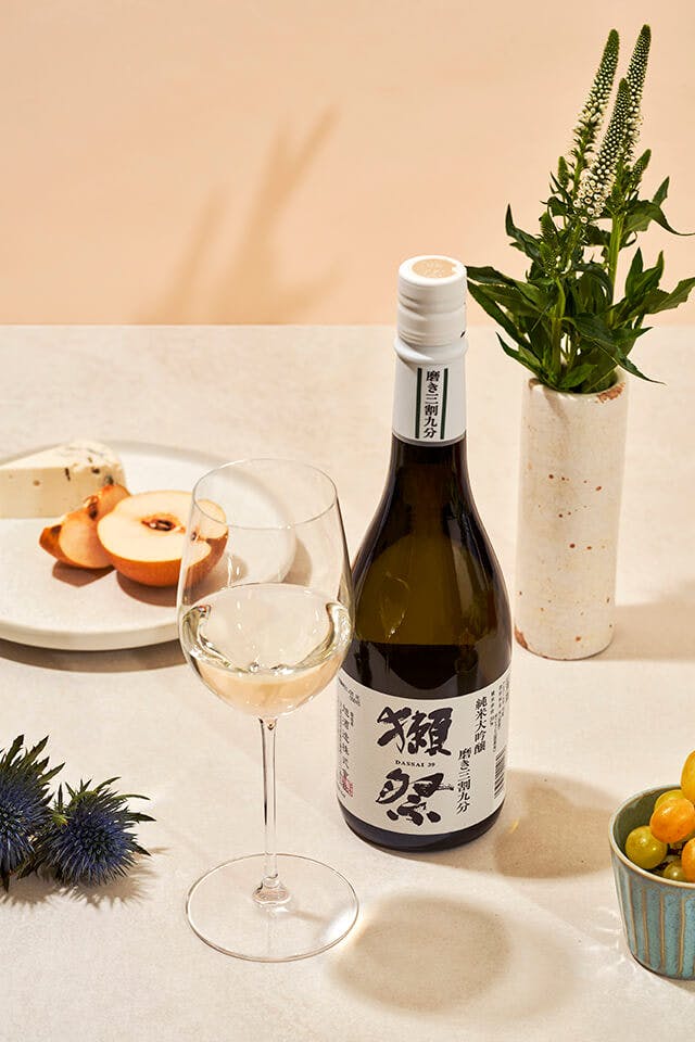 Dassai “39” Junmai Daiginjo with a wine glass, served with cheese and fruits